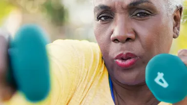 Older woman punching the air like a boxer while holding four pound weights